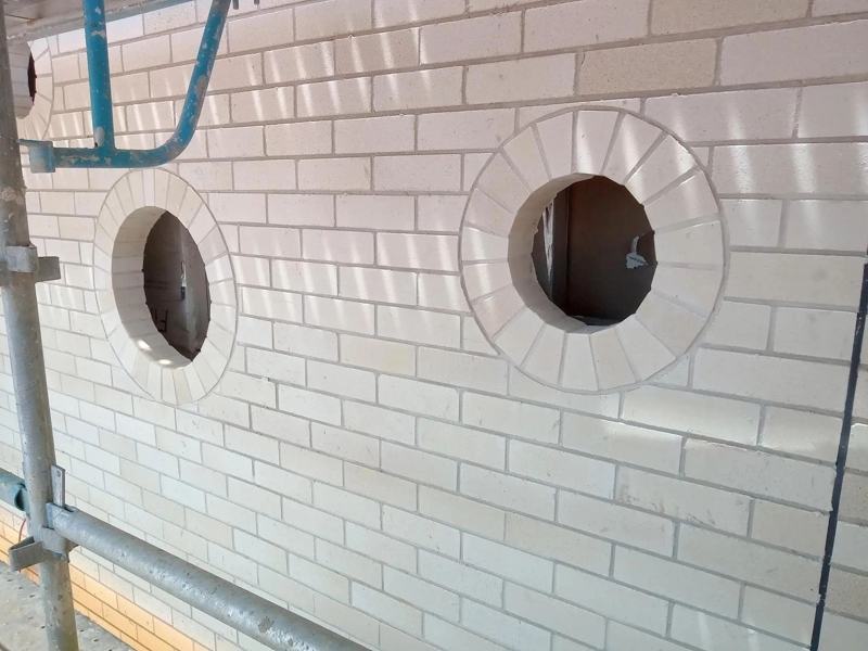 New face brickwork with arched brick surrounds on porthole windows